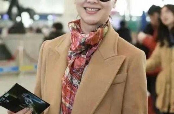 左小青携女儿走机场，穿驼色大衣配牛仔裤好减龄，彩色围巾显气质